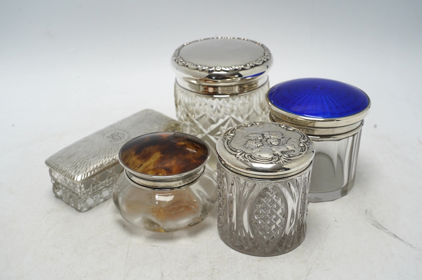 A collection of thirteen assorted late Victorian and later silver topped toilet jars, including blue enamel, tortoiseshell and repousse silver, tallest 9.9cm. Condition - poor to fair to good
